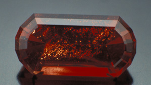 The Ponderosa Queen is a superb 10.79-ct. deep red faceted sunstone from the Ponderosa mine in Oregon. The copper inclusions that cause the characteristic aventurescence of that mine’s sunstones are clearly visible.