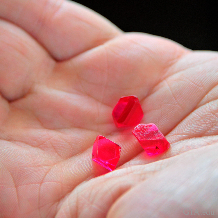 Hand holding hot pink spinel crystals, the August birthstone, in Man Sin, Myanmar’s Mogok Stone Tract. Hand holding hot pink spinel crystals, the August birthstone, in Man Sin, Myanmar’s Mogok Stone Tract.