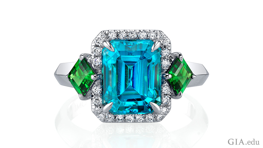 Handcrafted December birthstone ring with a 6.59 carat emerald cut blue zircon center stone accented by emerald cut tsavorite garnets, and brilliant diamond rounds set in 18K white gold. Handcrafted December birthstone ring with a 6.59 carat emerald cut blue zircon center stone accented by emerald cut tsavorite garnets, and brilliant diamond rounds set in 18K white gold.